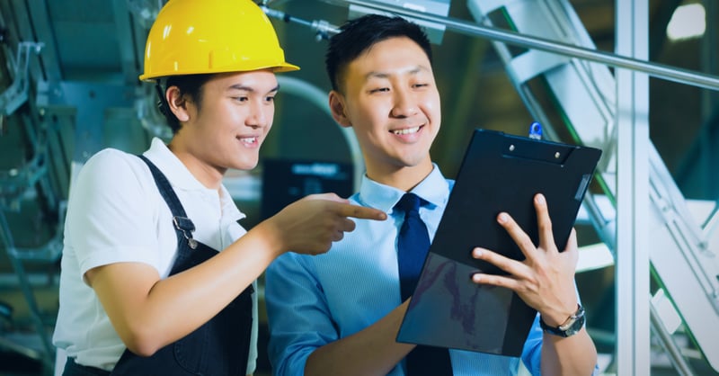 Construction worker and manager planning and looking at clipboard