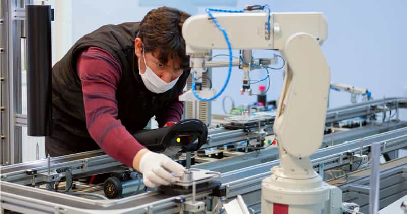 Factory worker doing maintenance on robotic arm
