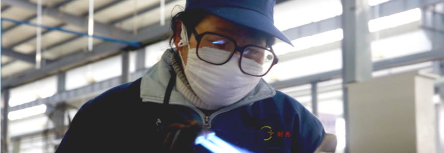 Chinese factory worker welding while wearing a mask
