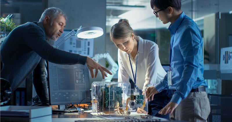 three people working and discussing a machine