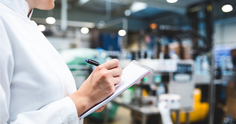 a woman in a factory taking down notes on production