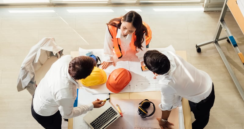 Factory workers gathered around a project plan laid out on the table. 