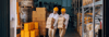 two factory workers carrying heavy boxes inside the manufacturing plant.