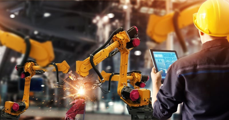 Engineer monitoring automated welding robot in an automotive factory
