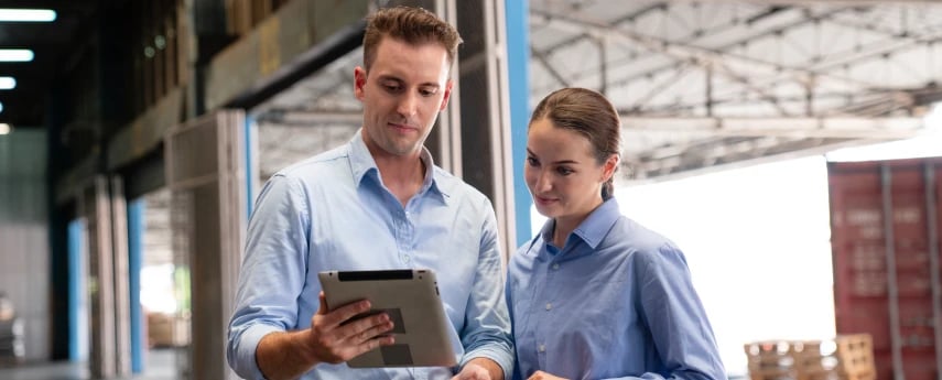 a man and women looking at a tablet in a warehouse