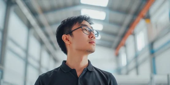 man with glasses standing inside a brightly lit warehouse